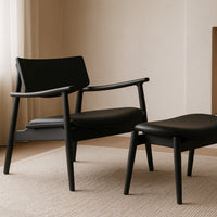 Black armchair and ottoman on a beige carpet with a neutral wall background