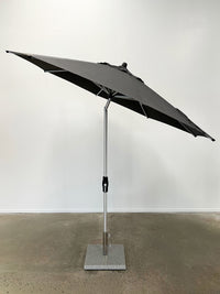 grey patio umbrella on a stand against a white wall