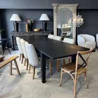 Dining room with a dark wooden table and various chairs against a gray wall.