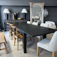 Dining room with a black table and various chairs, including wooden and gray chairs.