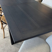 Dark wooden dining table with a chair and cushion in the foreground