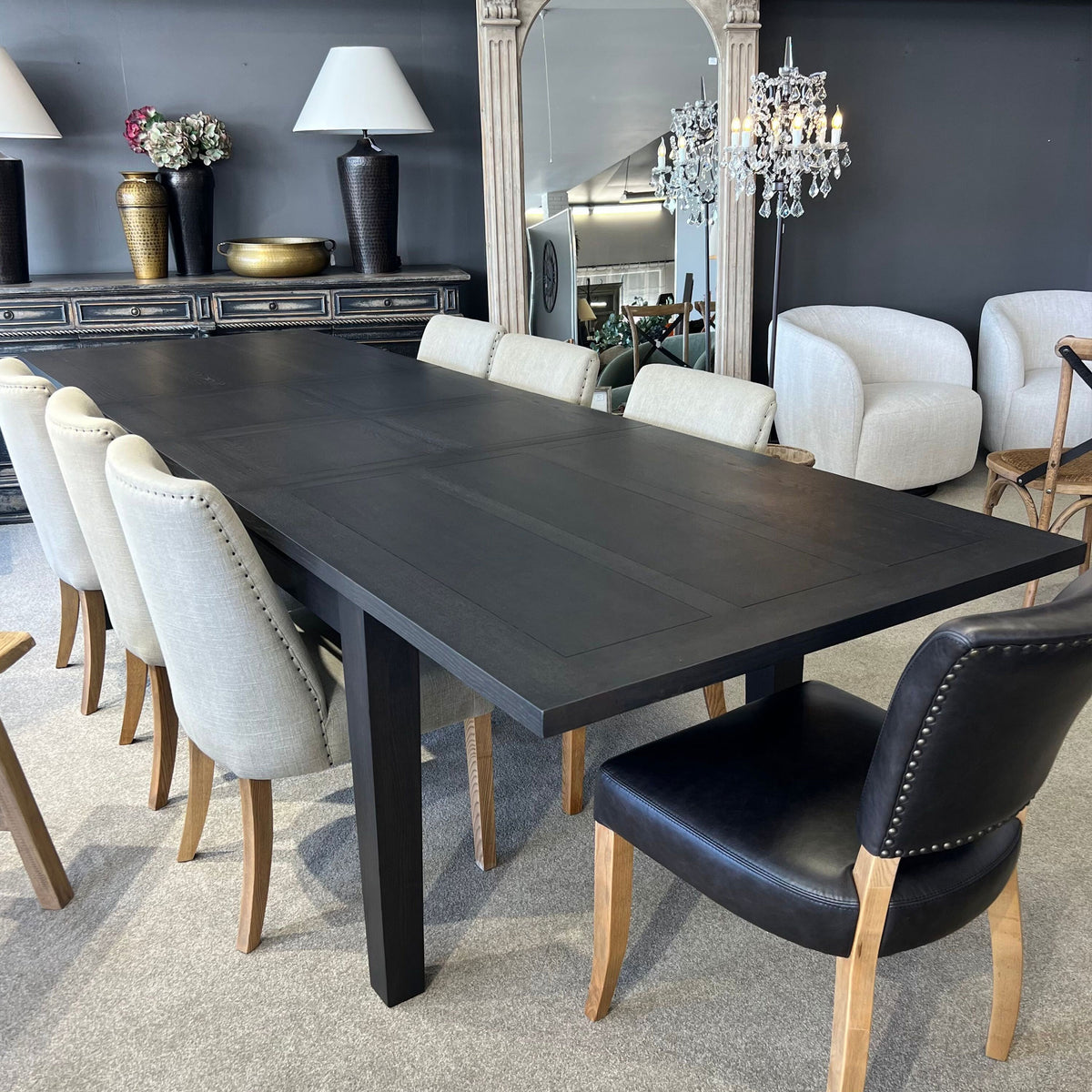 Dining room with a long black table and various chairs in a stylish interior setting.
