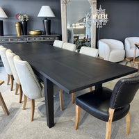 Dining room with a long black table and various chairs in a stylish interior setting.