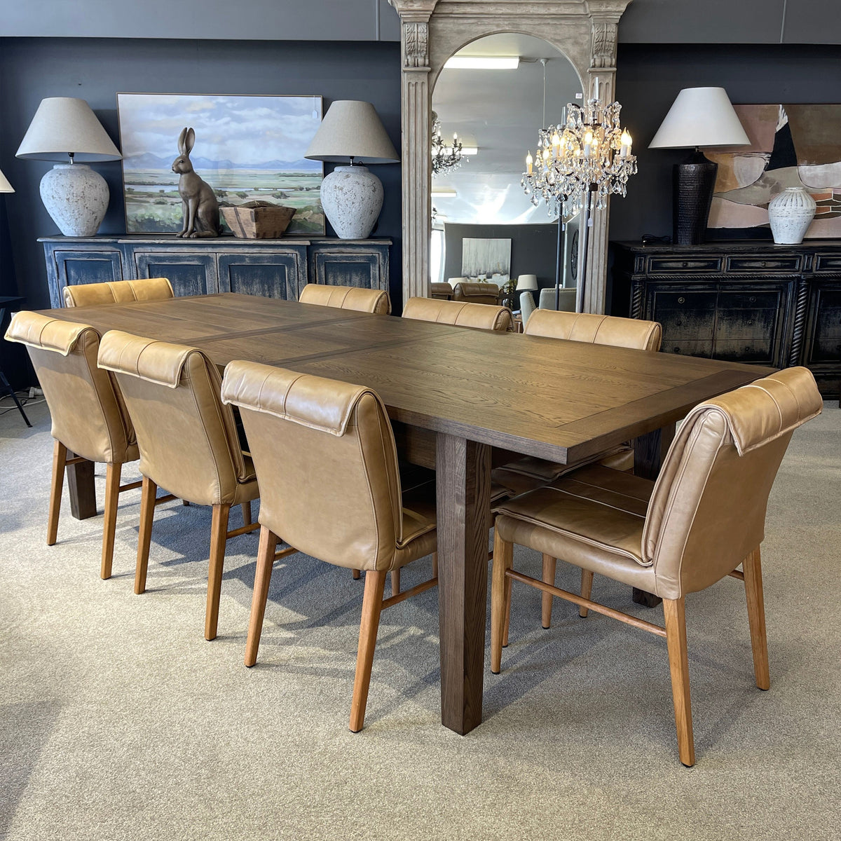 Dining room with a wooden table and beige chairs, decorated with wall art and lamps.