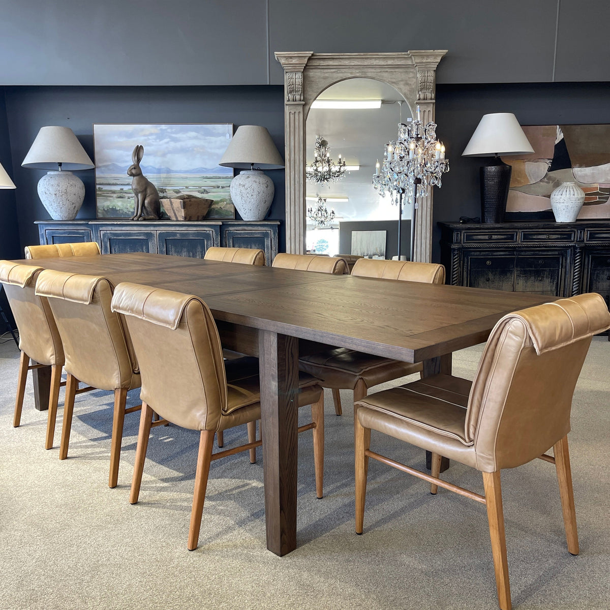 Dining room with wooden table and brown chairs, decorated with lamps and a mirror.