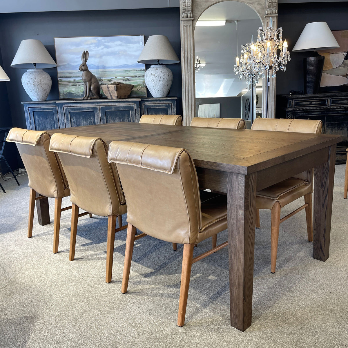 Dining room with wooden table and leather chairs, decorative elements, and a chandelier.