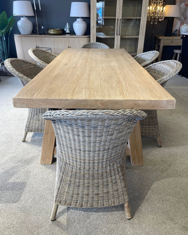 Dining room with a wooden table and wicker chairs on a carpeted floor.