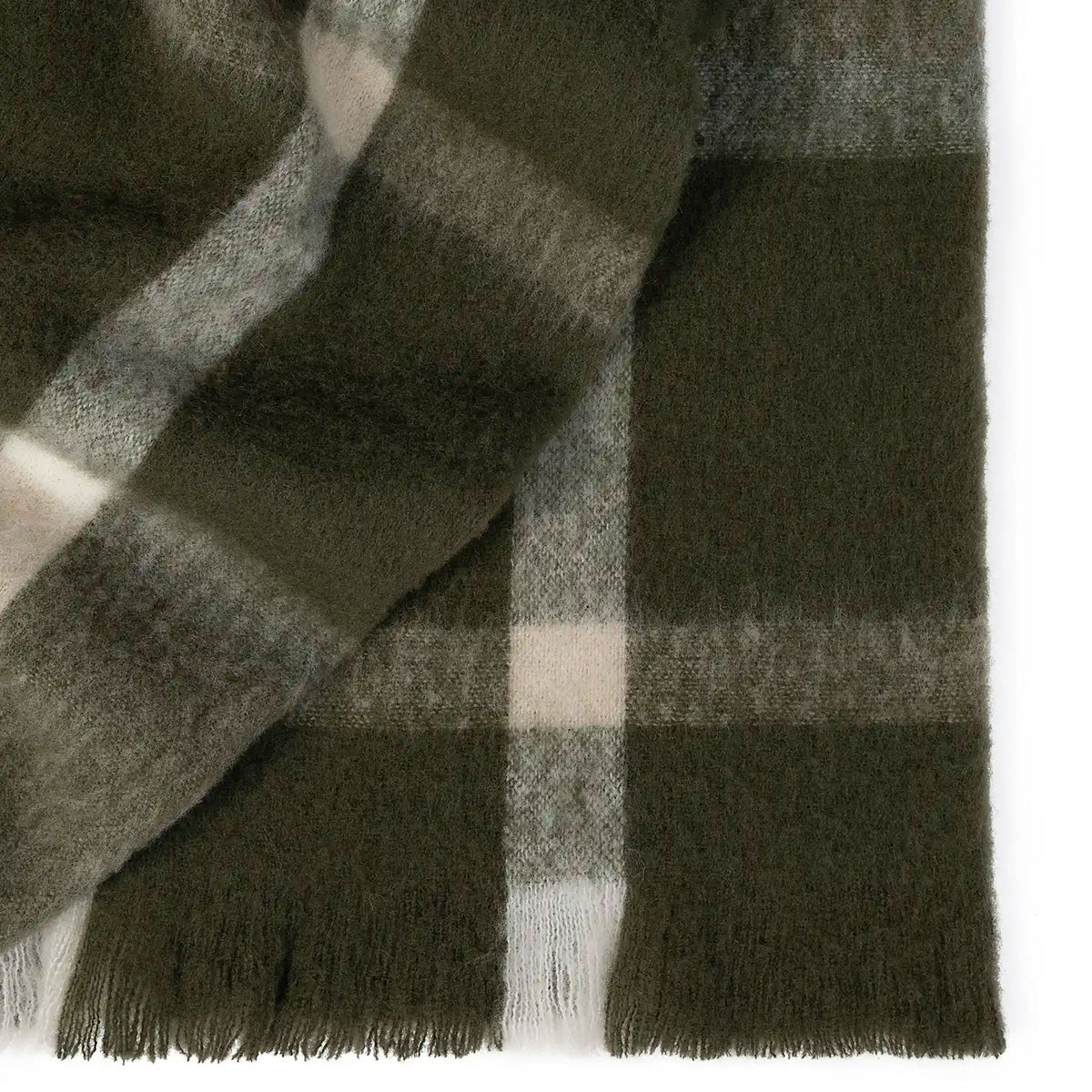 Close-up of a green plaid throw with fringes on a white background