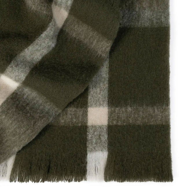 Close-up of a green plaid throw with fringes on a white background