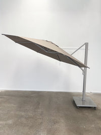 Beige outdoor umbrella on a stand against a white wall