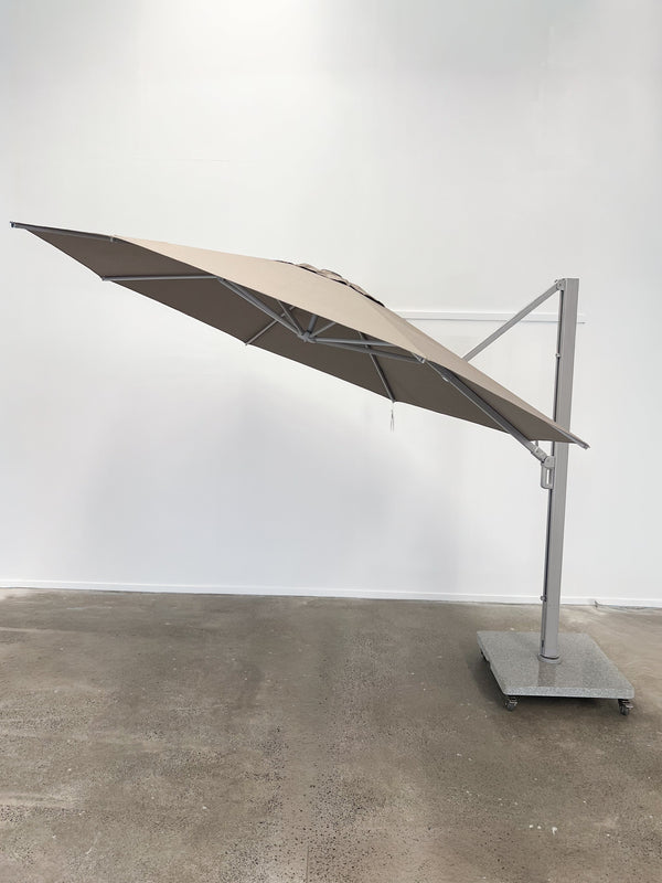 Beige outdoor umbrella on a stand against a white wall